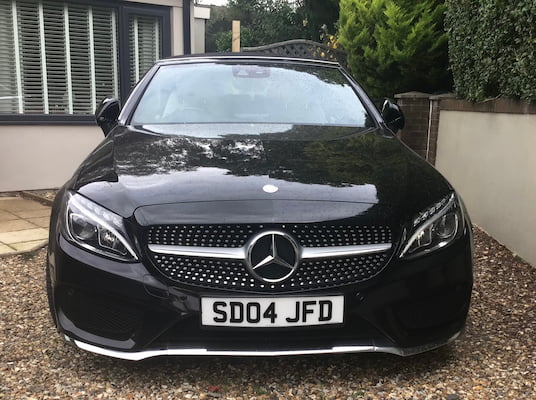 A photograph of a black car displaying a plate which reads 'SD04 JFD'